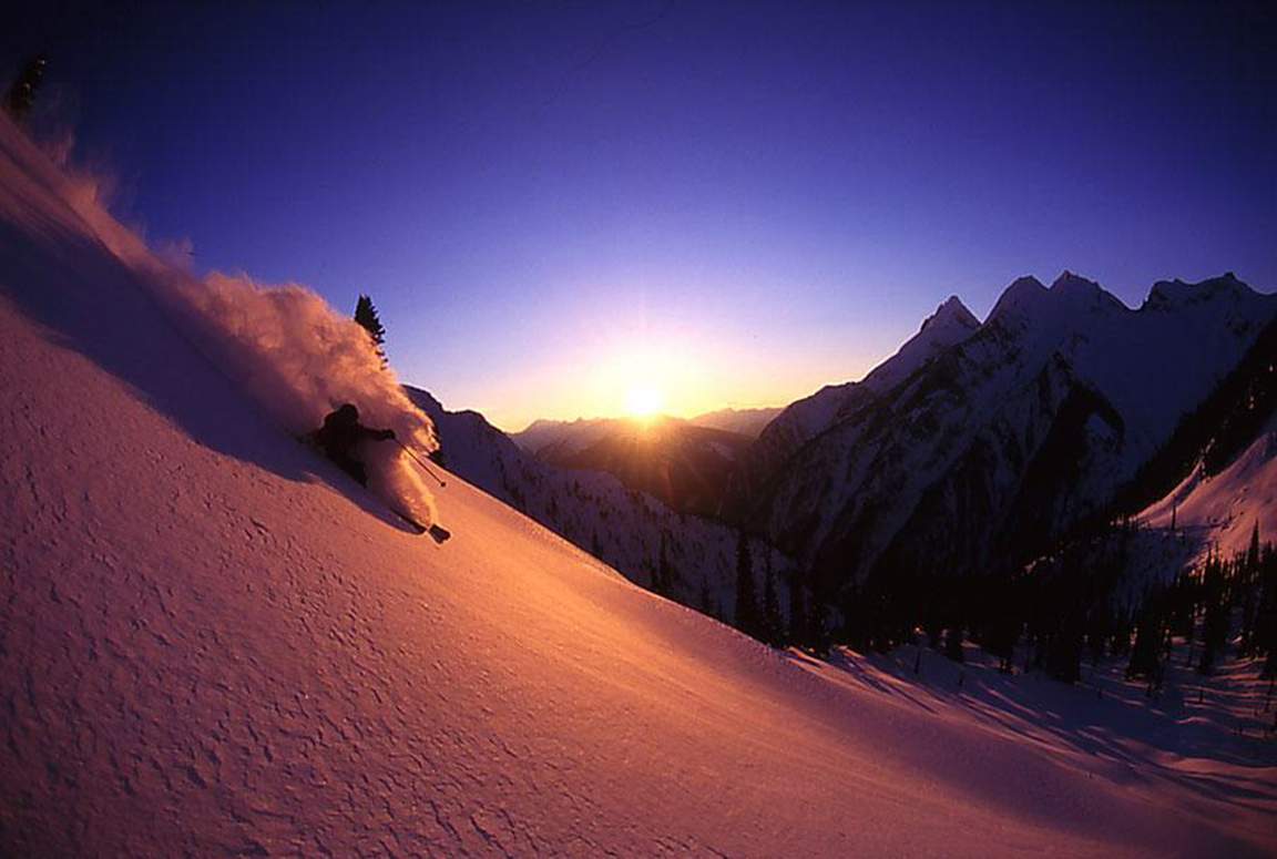 Skier in deep powder at sunset in the mountains