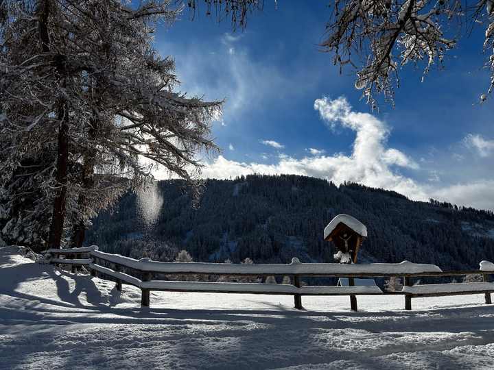 Snow-covered wooden fence and wayside cross on a winter walking trail