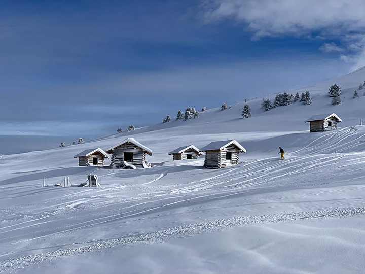 Snow-covered hay barns on the high plateau with a fresh ski track